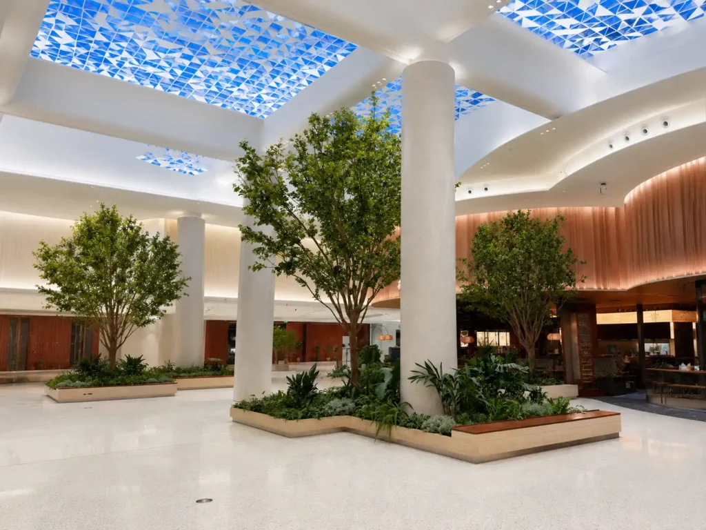 Finished commercial atrium landscape with custom artificial trees and planting base